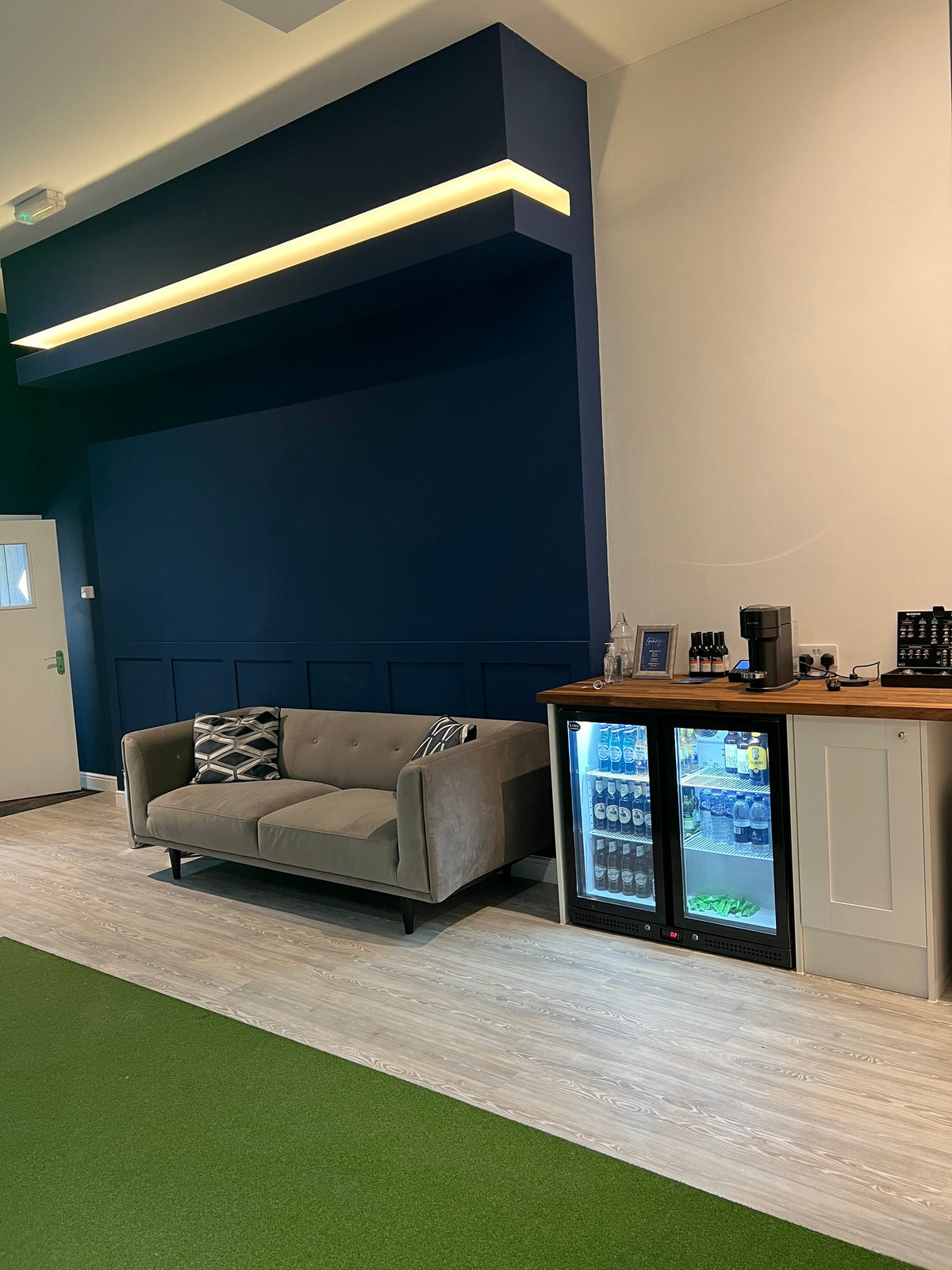 Lounge area with sofa and drinks fridge at The Golf Lounge, Birstall